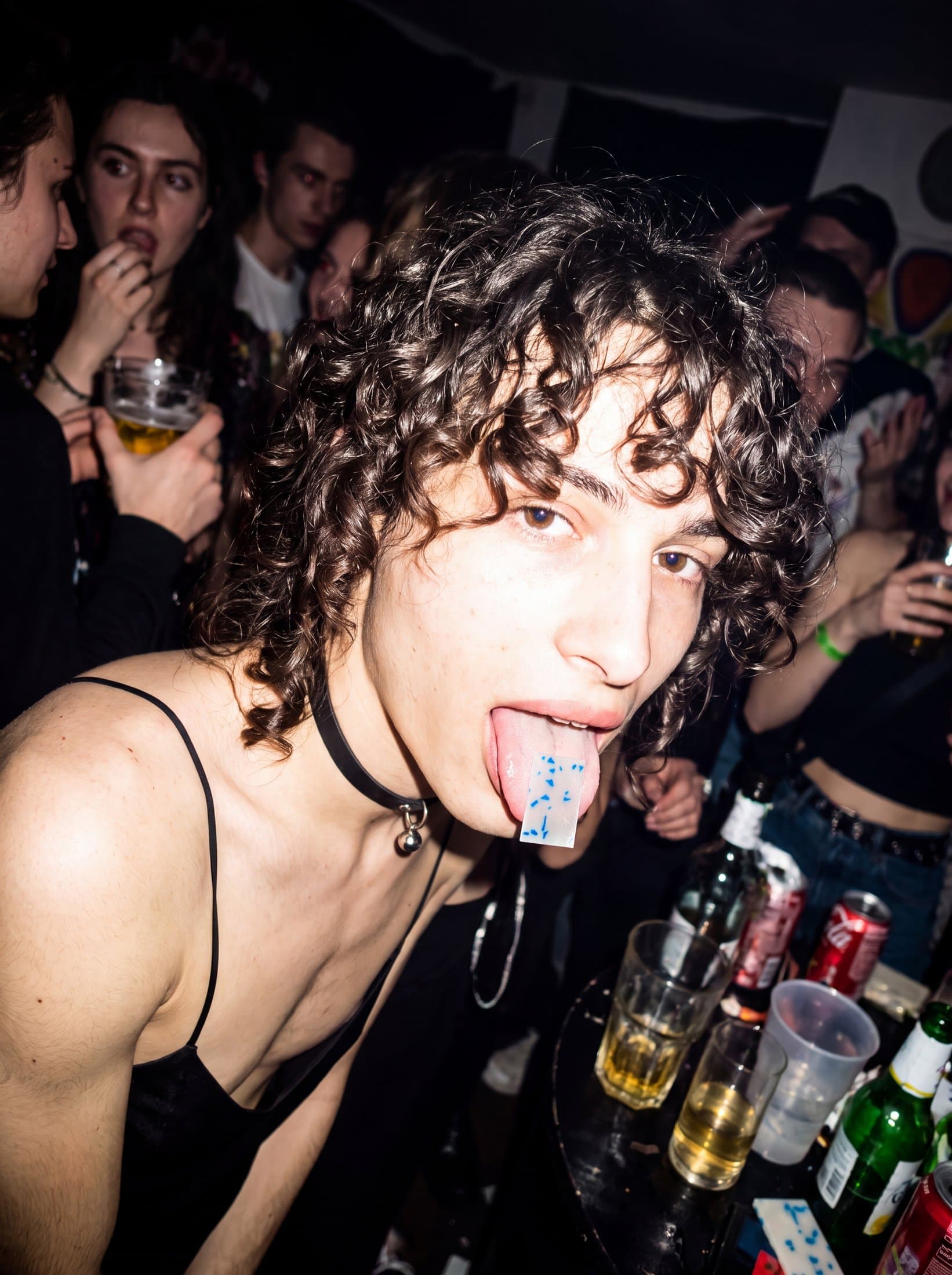A Rally hydration strip resting on someone's tongue in a crowded club